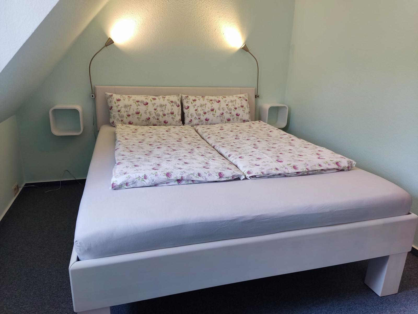 Schlafzimmer mit Doppelbett, floraler Bettwäsche und zwei Wandlampen.