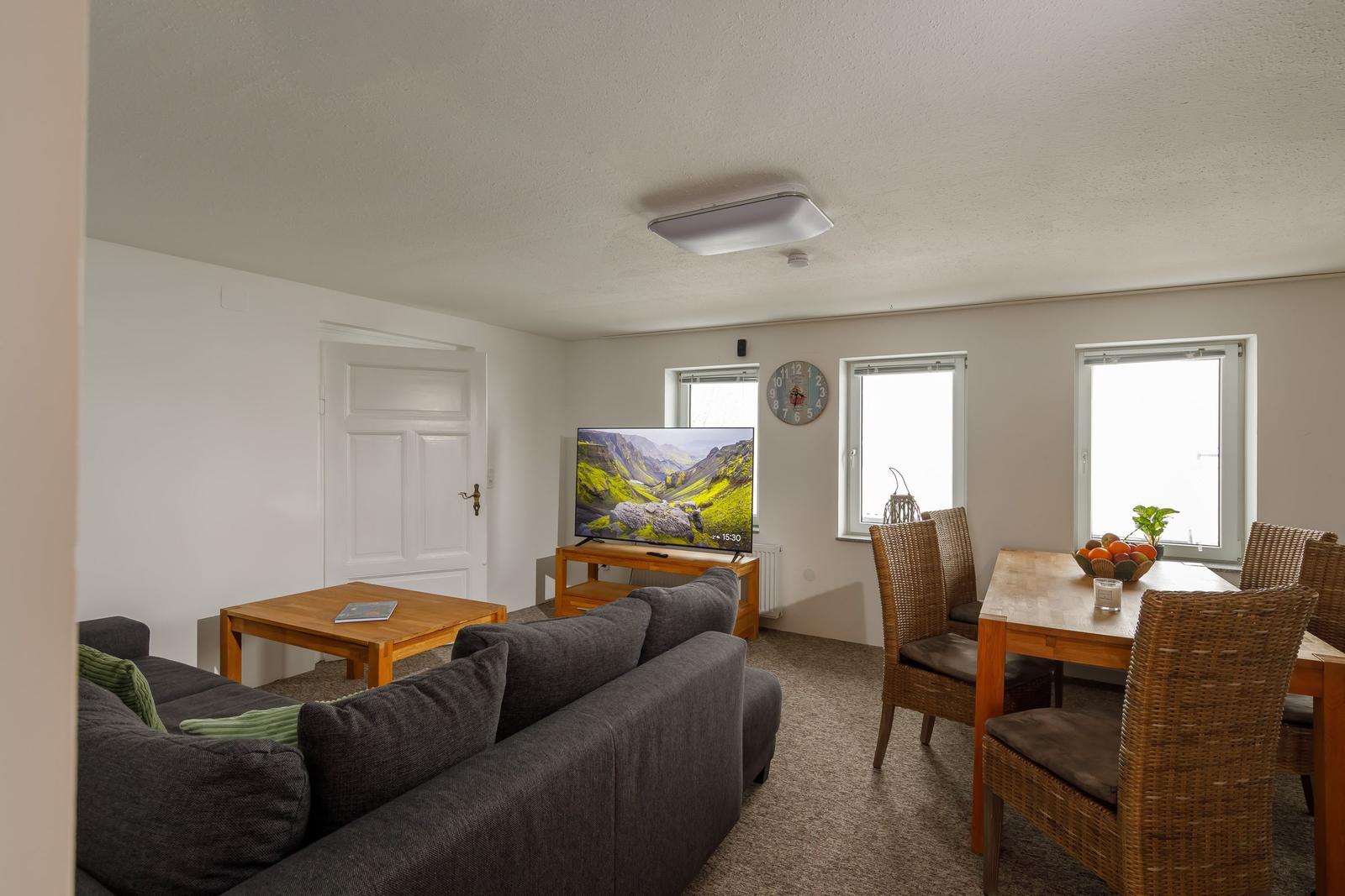 Wohn- und Essbereich mit Sofa, TV, Esstisch und Stühlen.