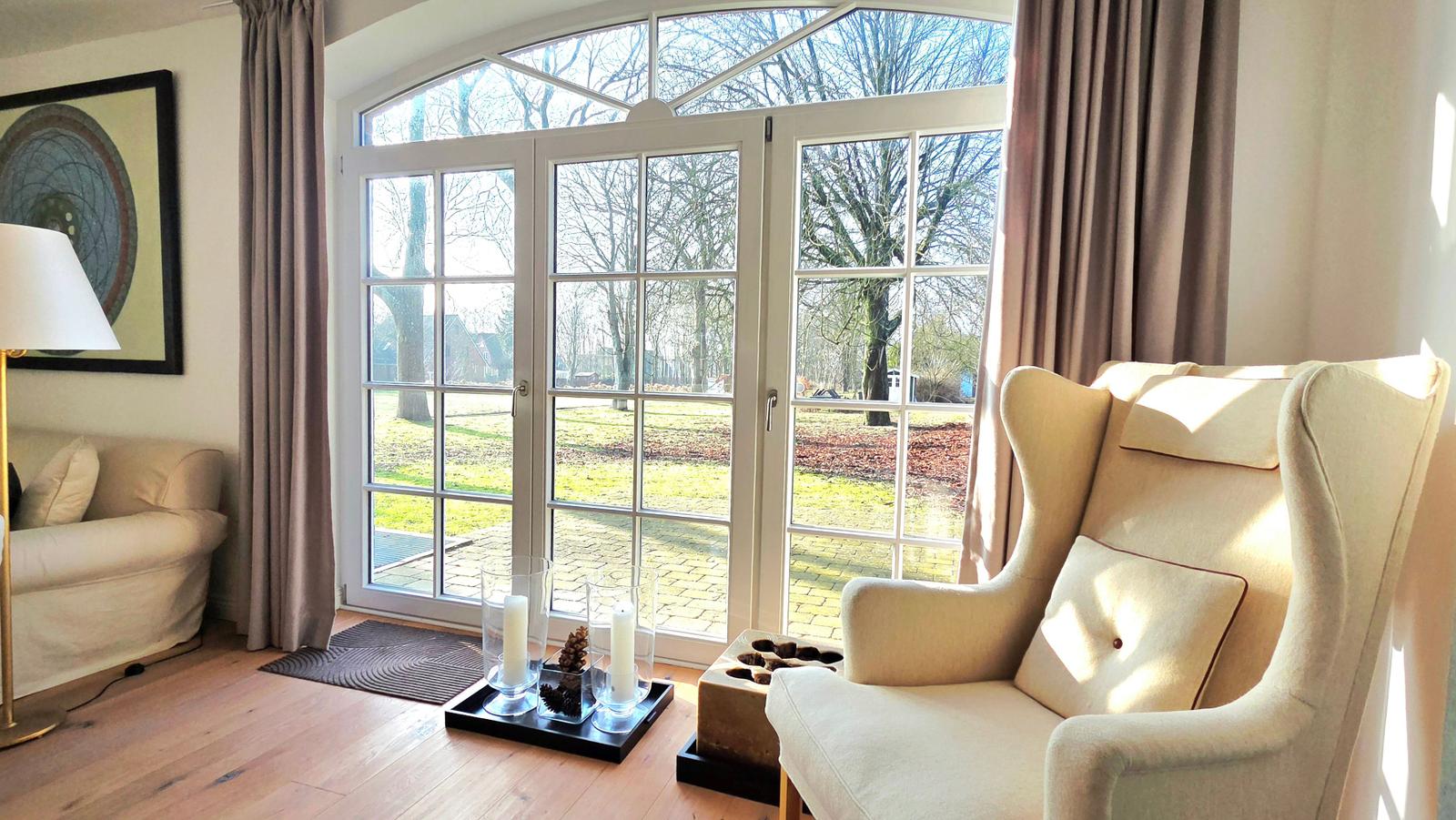 Lichtdurchfluteter Raum mit Sitzgelegenheiten und Blick auf den Garten.