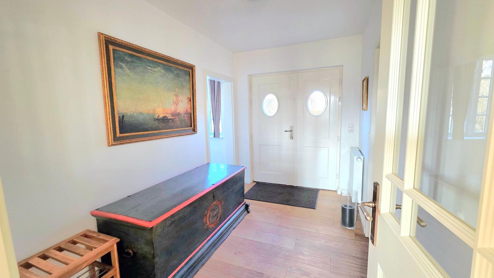 Eingangsbereich mit Holzboden, antikem Schrank und Wandgemälde