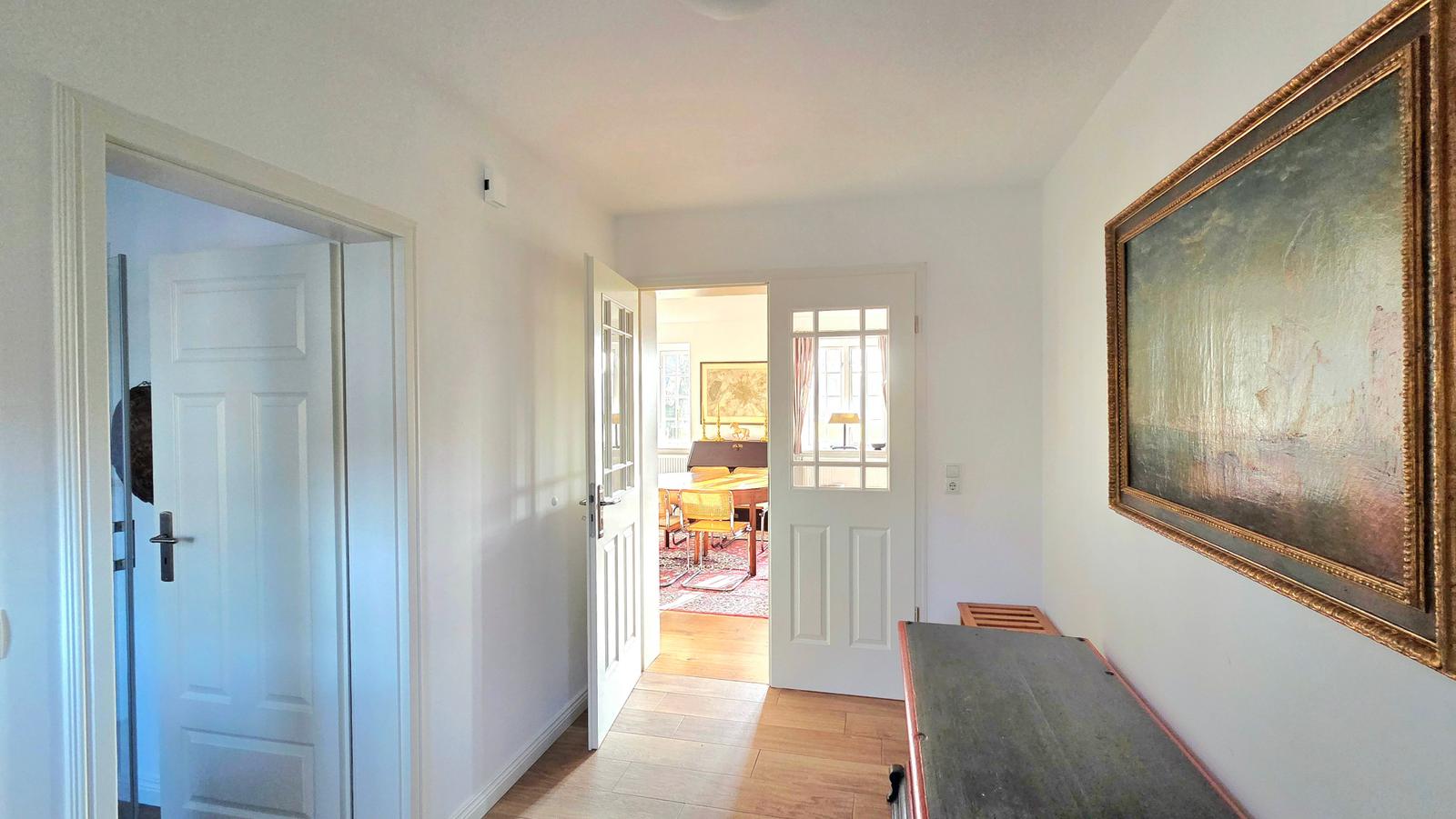 Flur mit Tür zu Schlafzimmer und Blick in Esszimmer mit Tisch und Stühlen.