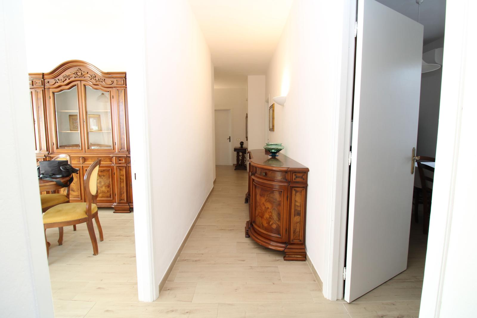 Hallway with wooden flooring, antique cabinet, and sideboard