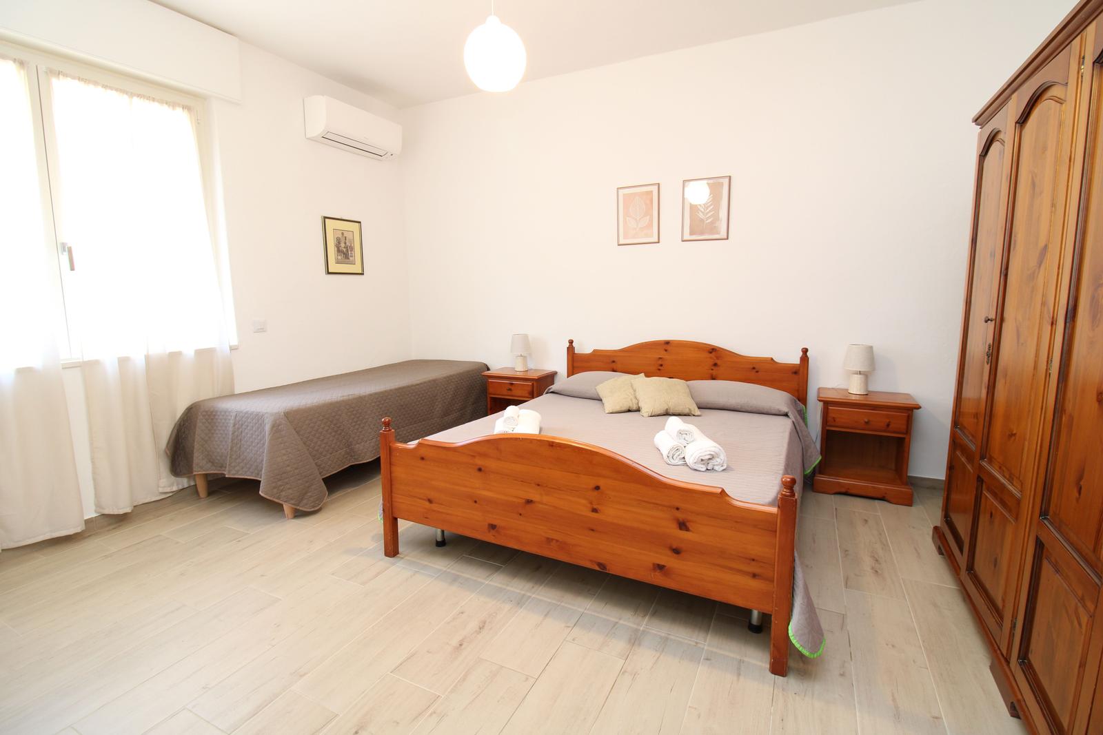 Bedroom with double bed, single bed, wardrobe, and nightstands.