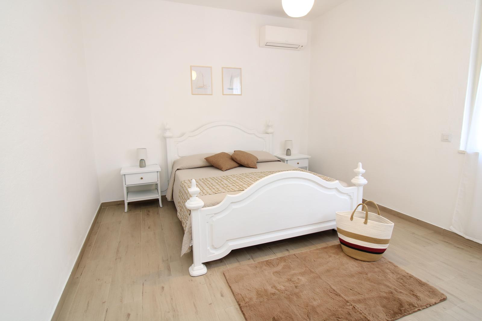 Bedroom with white bed, two nightstands, and wooden floor.