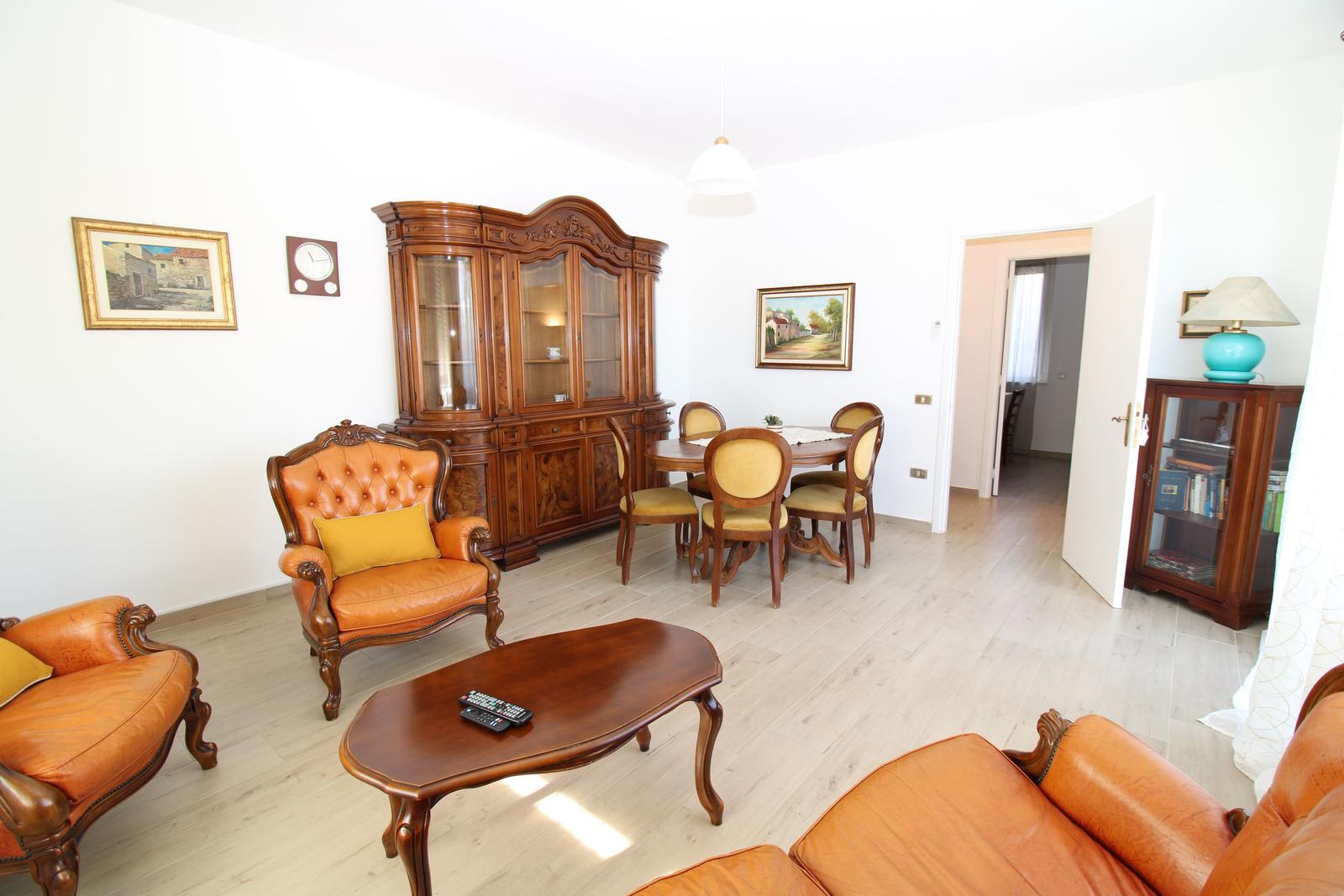 Living and dining area with wooden furniture and leather seating. 