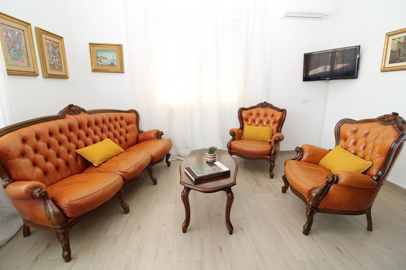 Living room with brown leather sofas, two armchairs, and a wooden table.