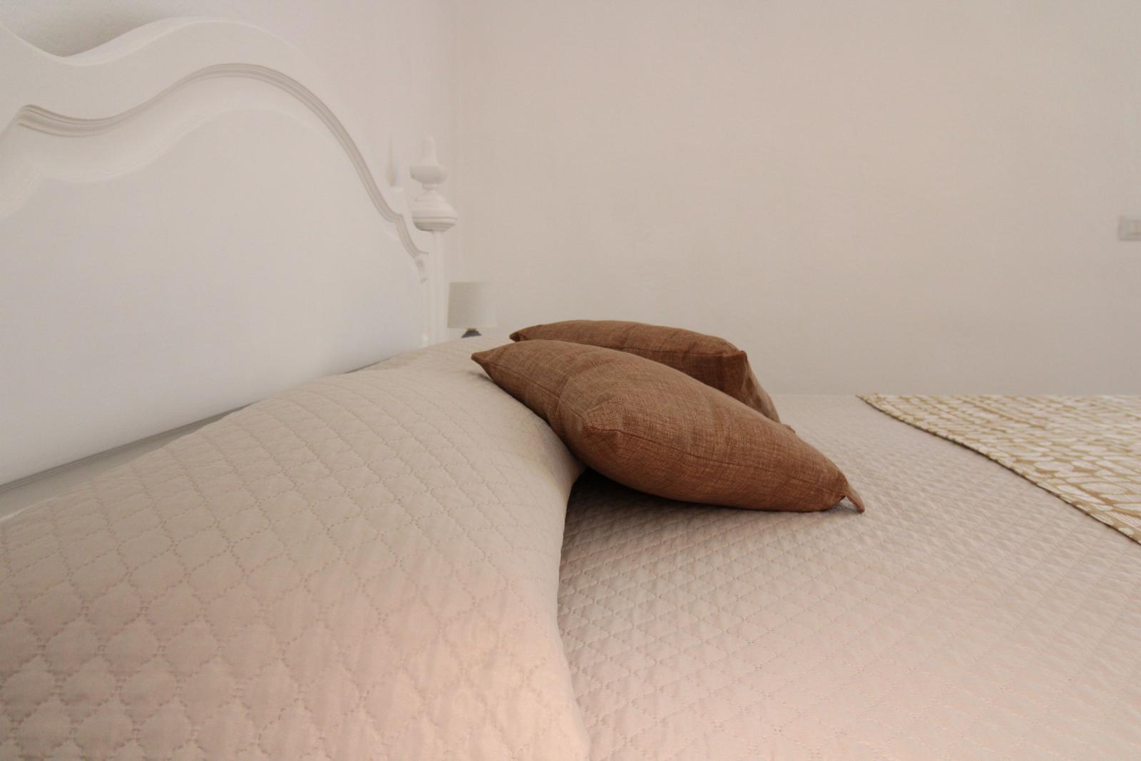 A bed with white headboard and brown pillows.