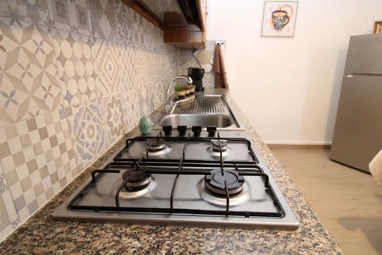 Kitchen with gas stove, sink, and mosaic wall
