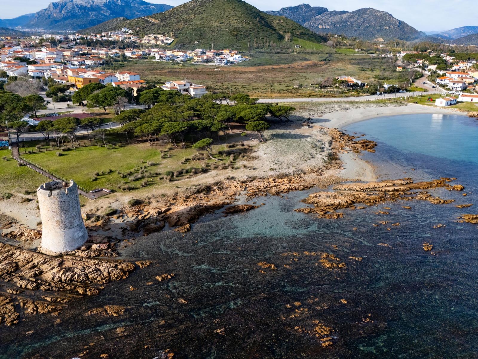 Old tower house by the shore with view of coastal landscape and town.