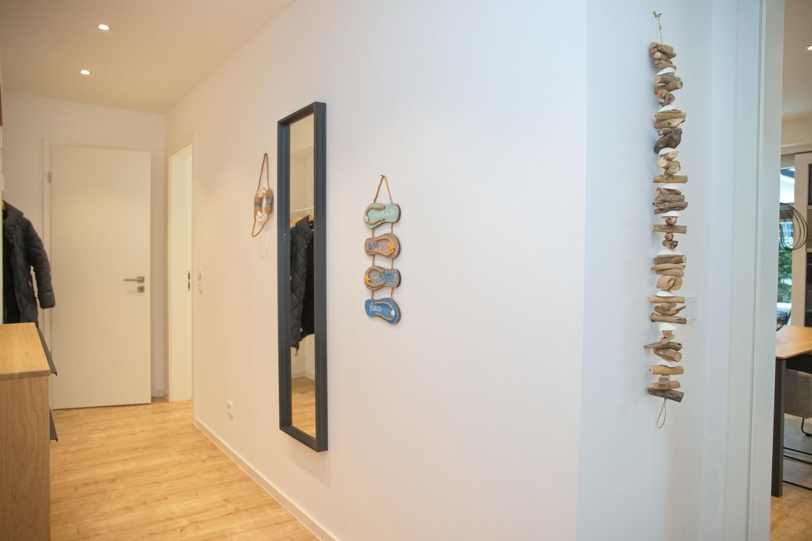 Flur mit Spiegel, Stranddekoration und Holzdekoration an der Wand.