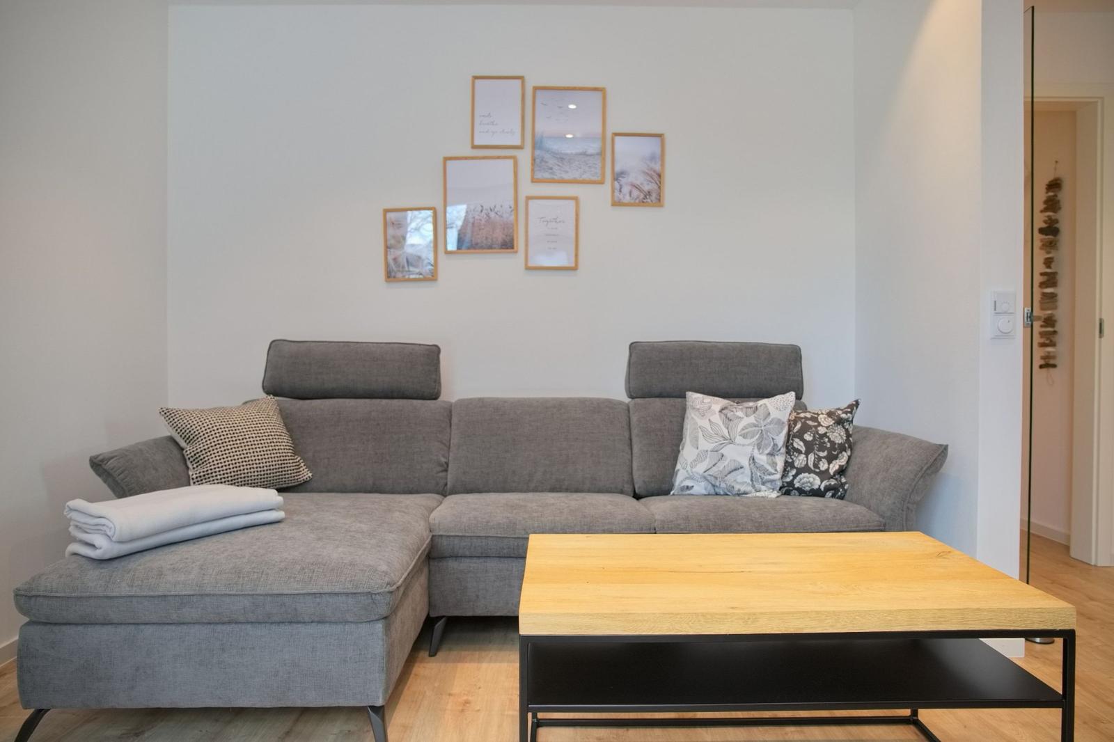 Ein grauer Sofa mit Kissen und einem Holztisch im Wohnzimmer.