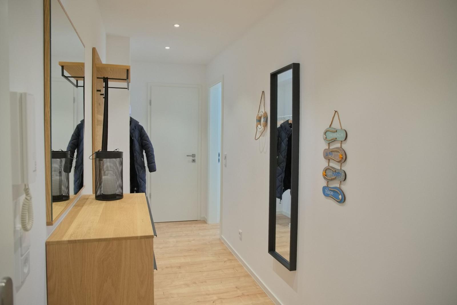 Flur mit Spiegeln, Kleiderständer und Wanddekoration.