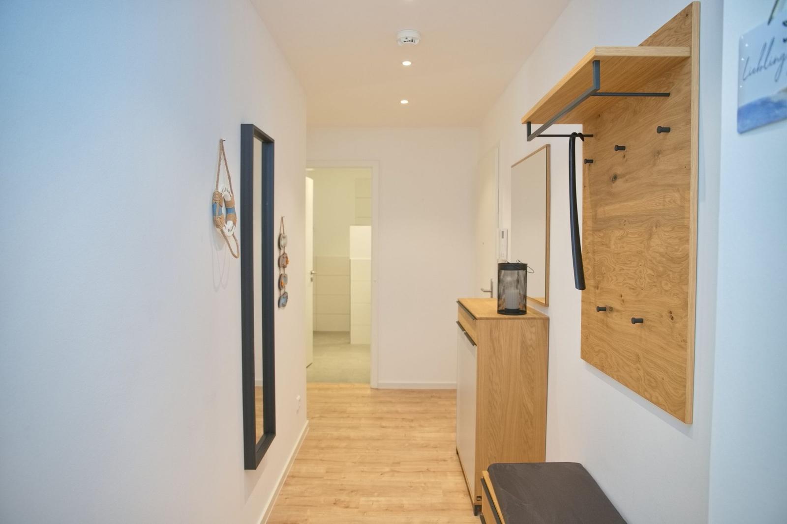 Flur mit Holzschuhschrank, Spiegel und dekorativen Wandelementen.