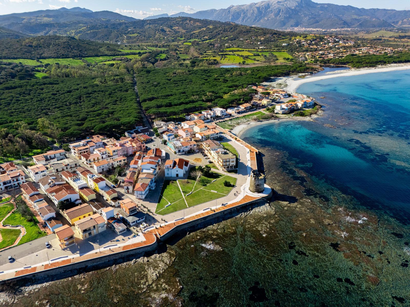 Kleines Dorf am Meer mit Blick auf Berge und grüne Landschaft.