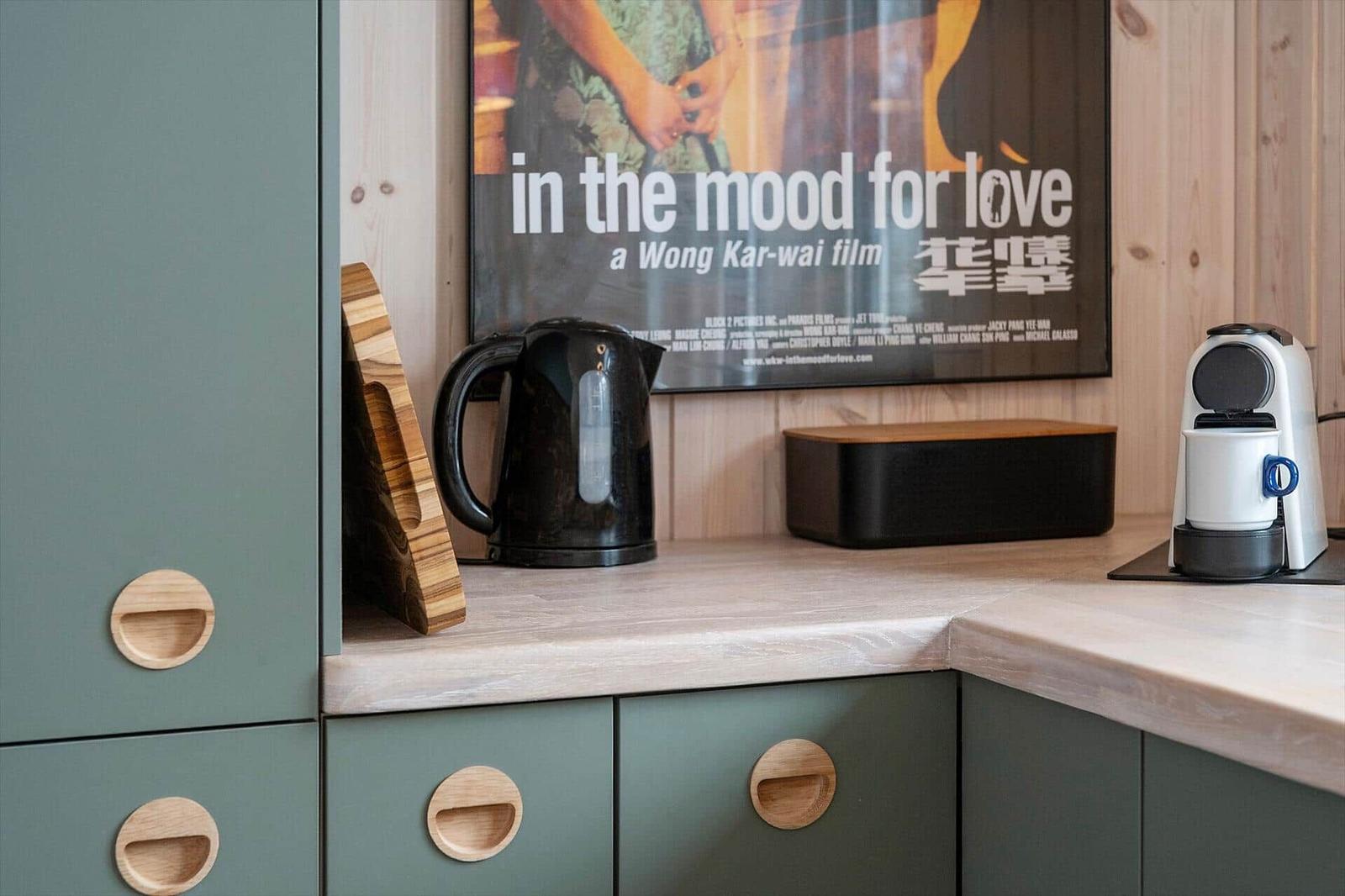 Kitchen area with coffee machine, kettle, and movie poster on the wall.