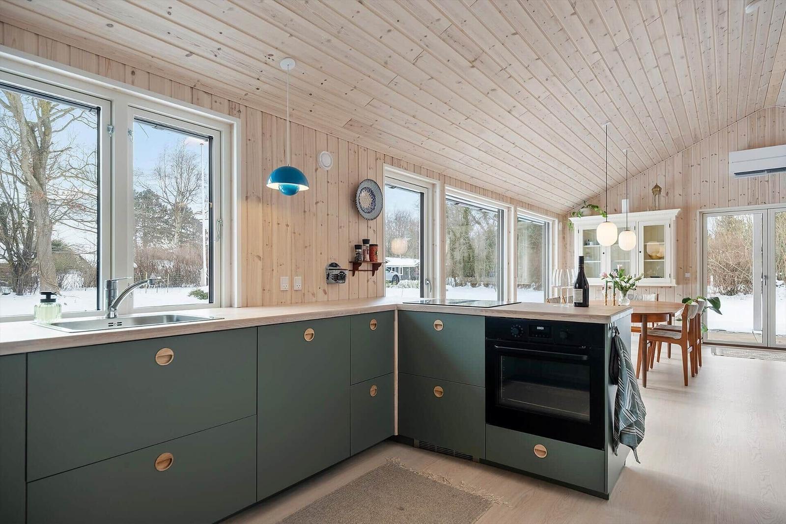 Kitchen with green cabinets, wooden ceiling, and view of snow.