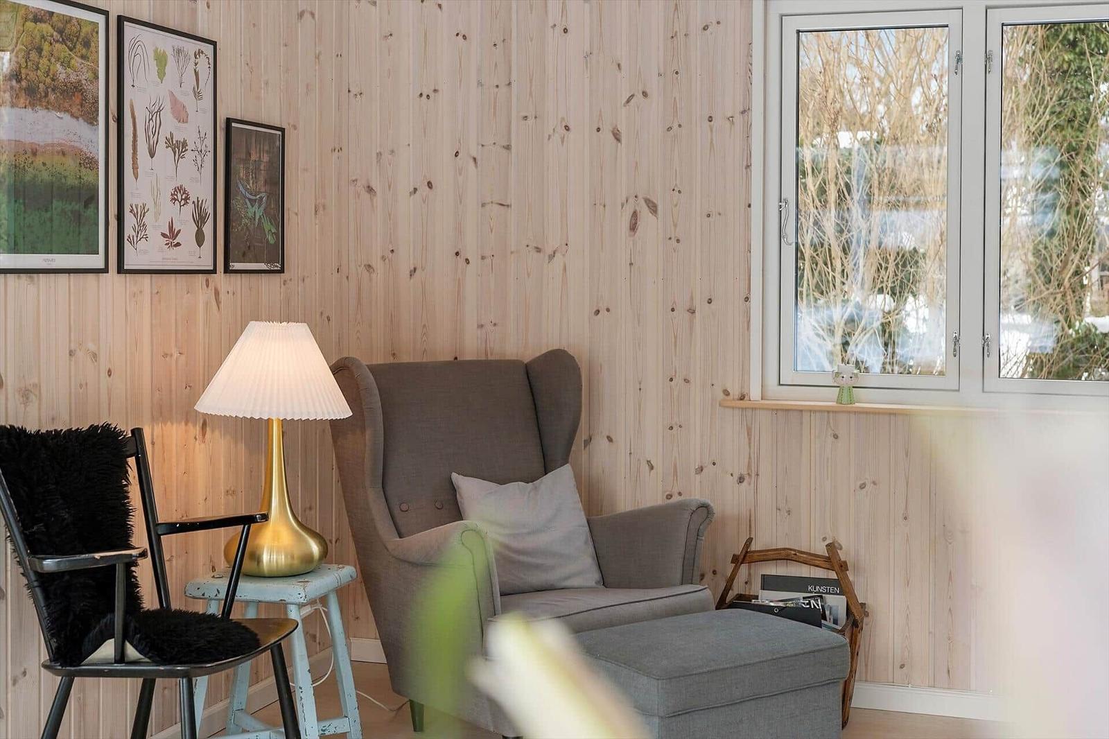 A room with wood wall, armchair, chair, and window.