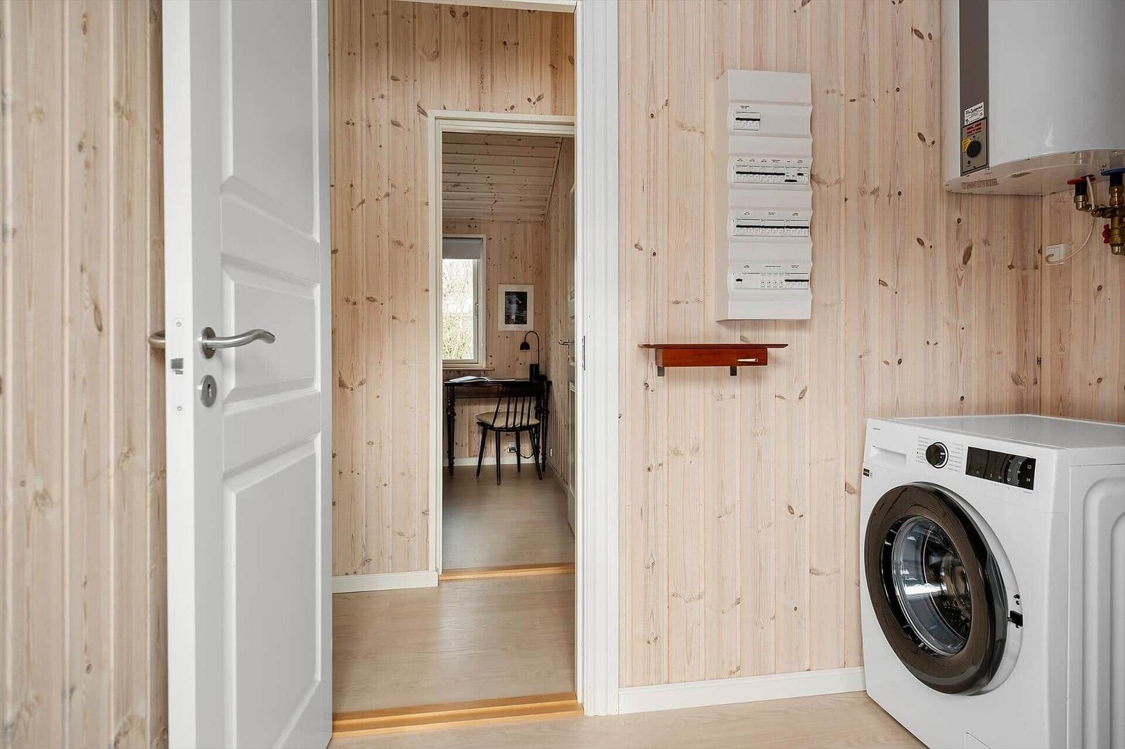 Laundry room with washing machine and heating control on wooden wall