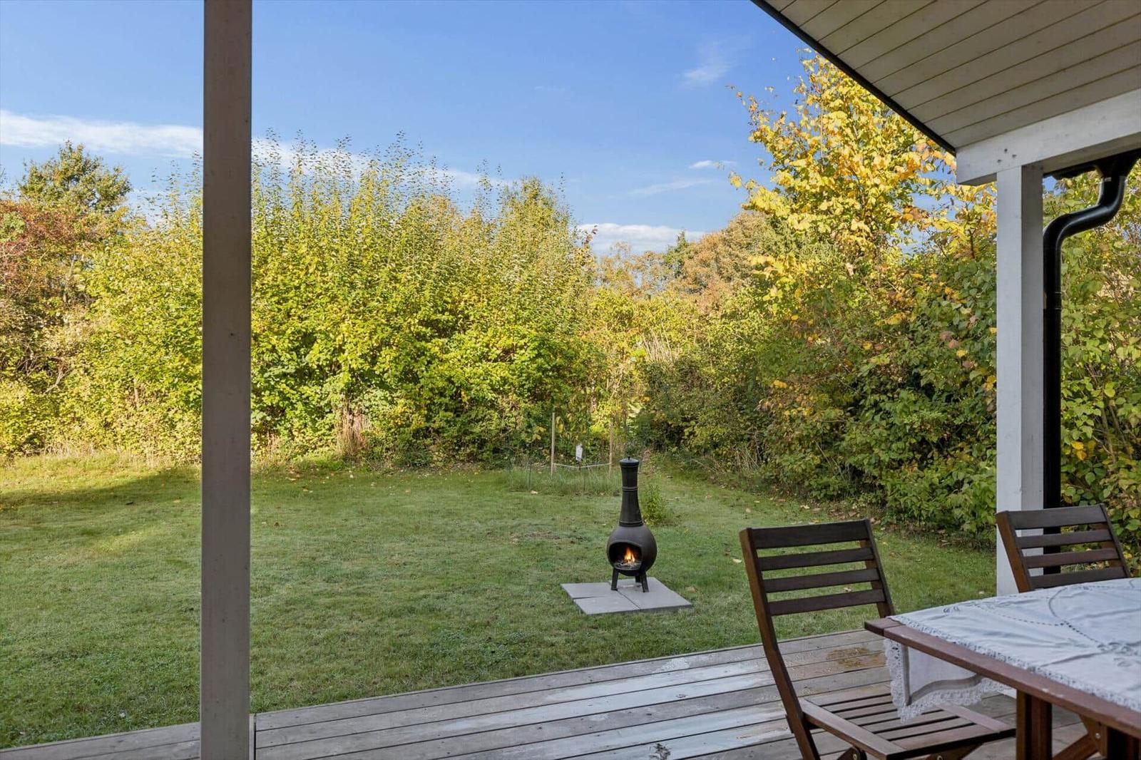 Deck with table, chairs, and fire pit in the garden.