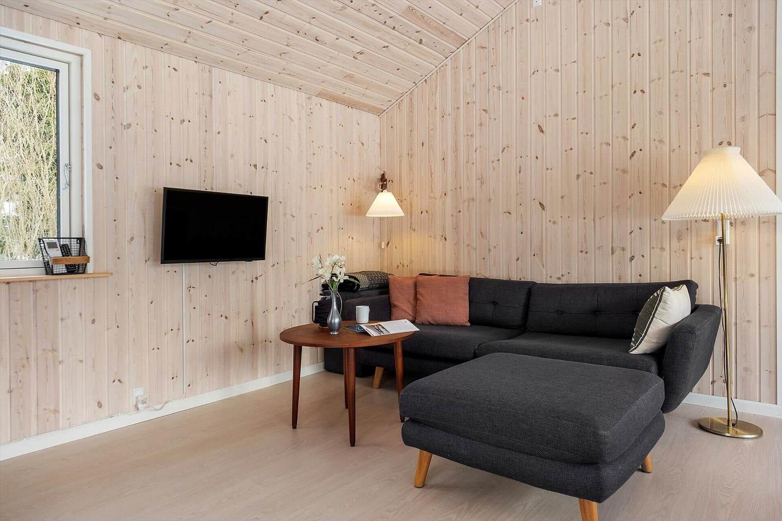 Living room with wooden walls, sofa, coffee table, and TV.