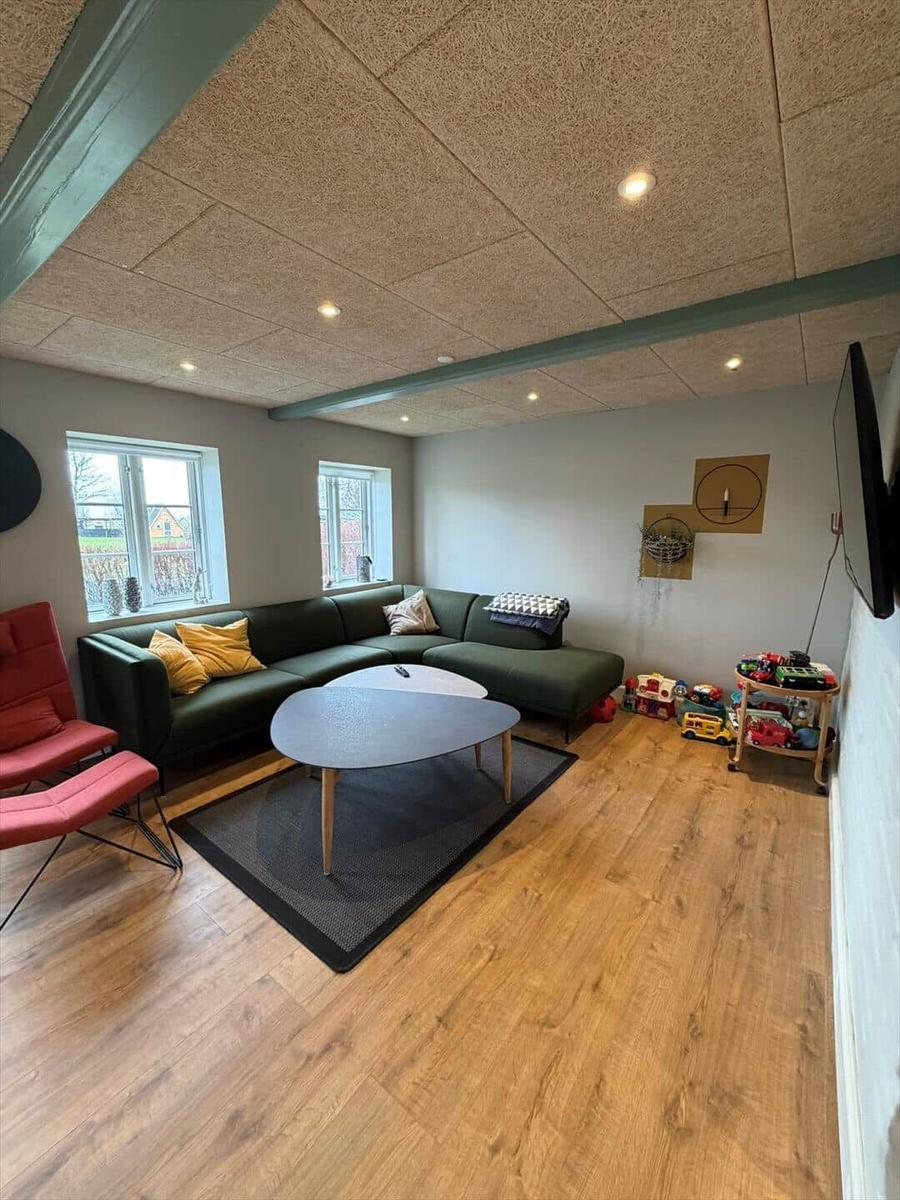 Living room with green sofa, round table, and wooden floor.