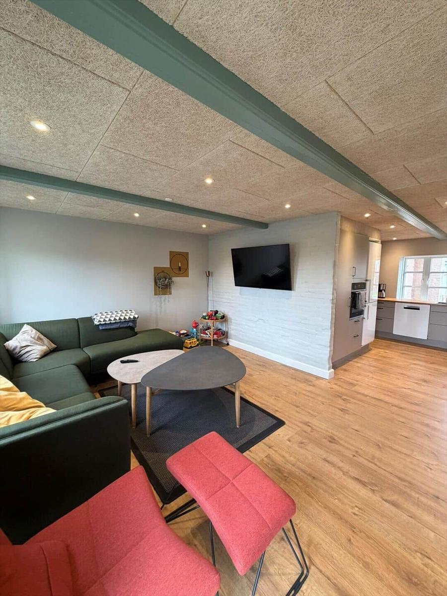 Living area with sofa, table, and TV. Kitchen with countertop and window.