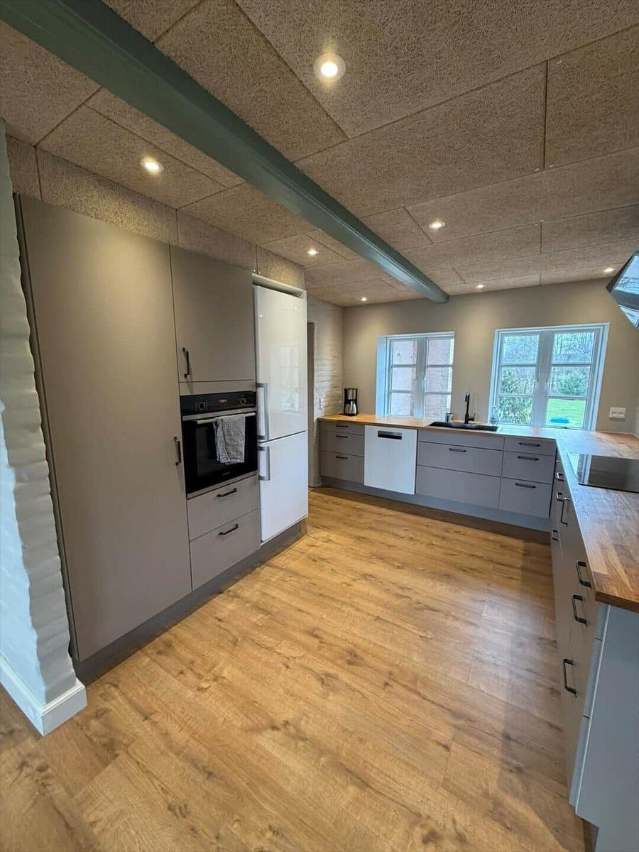 Modern kitchen with wooden floor, white cabinets, and built-in oven.