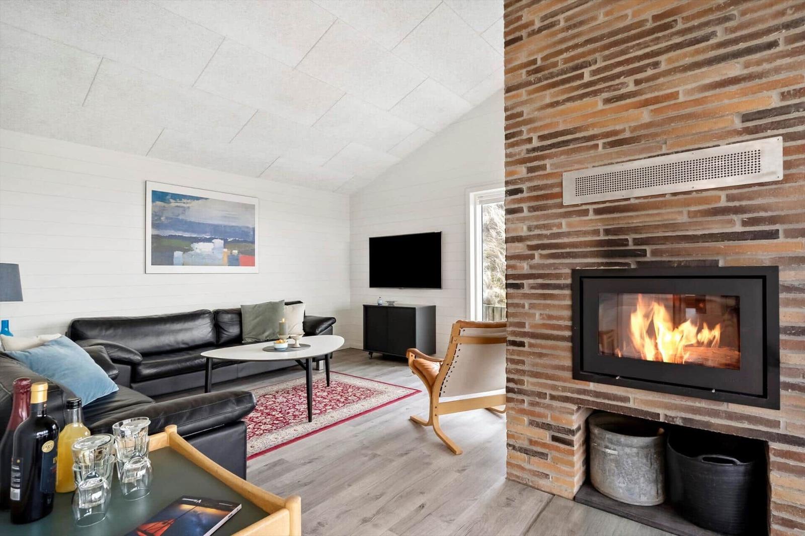 Wohnzimmer mit Kamin, Sofa, Fernseher und Holzboden.