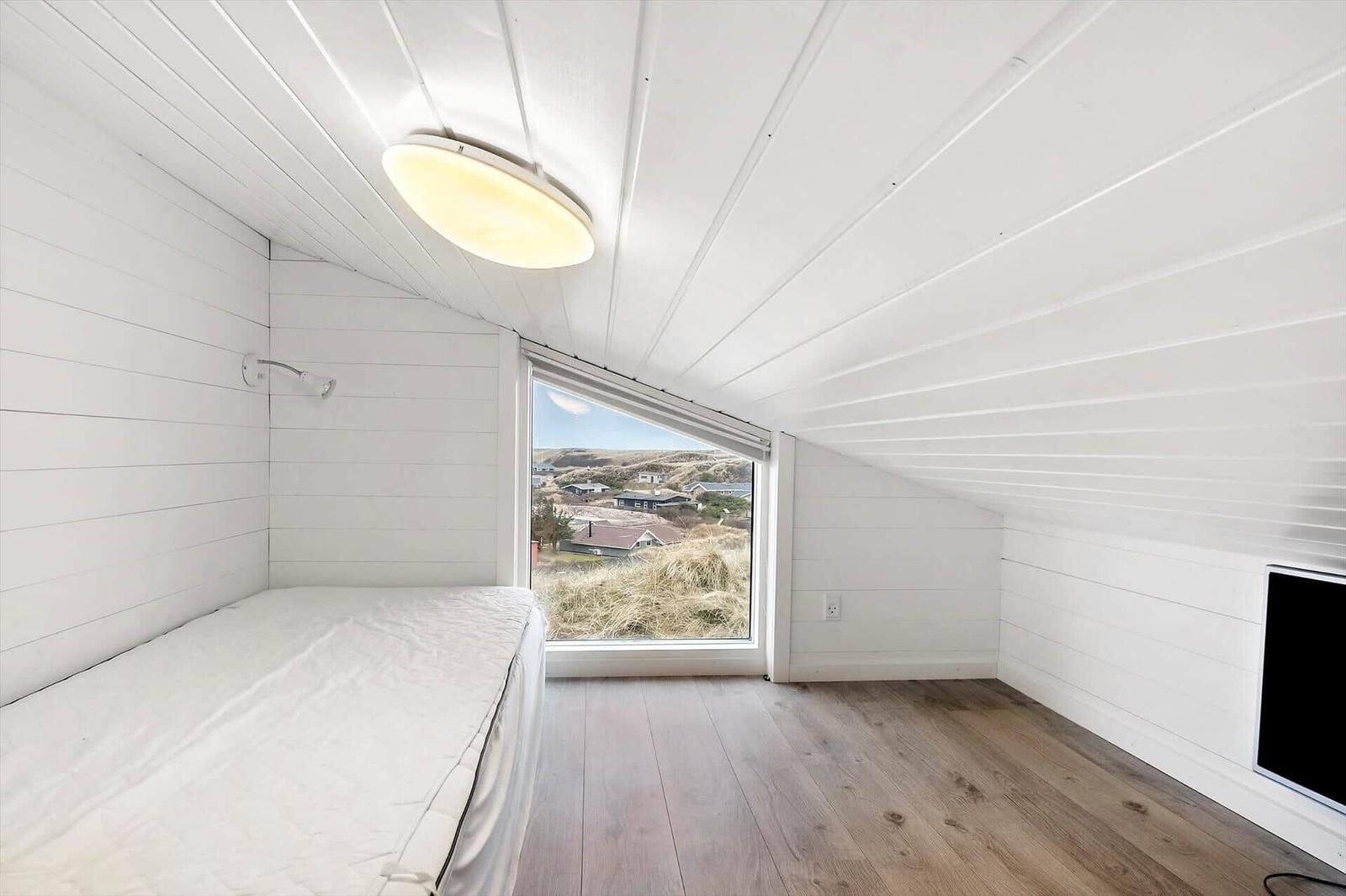 Zimmer mit Bett, Fenster und Holzboden. Blick auf die Landschaft.