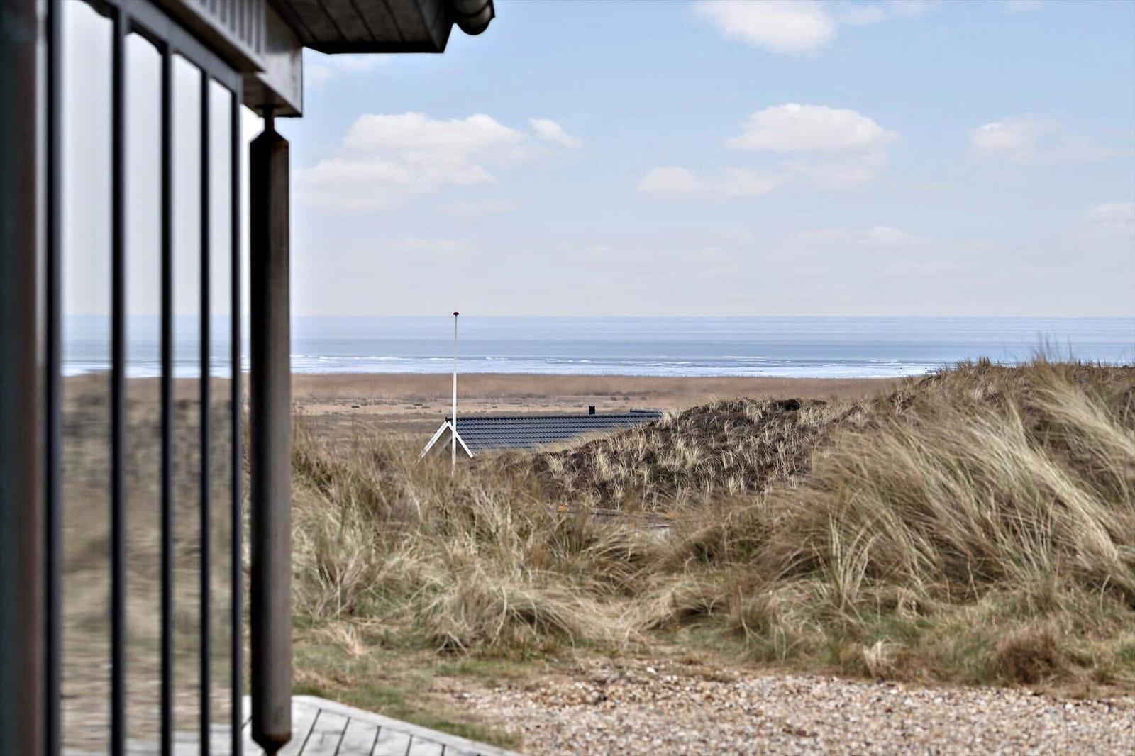 Blick vom Haus aus auf Strand und Meer mit Dünen im Vordergrund.