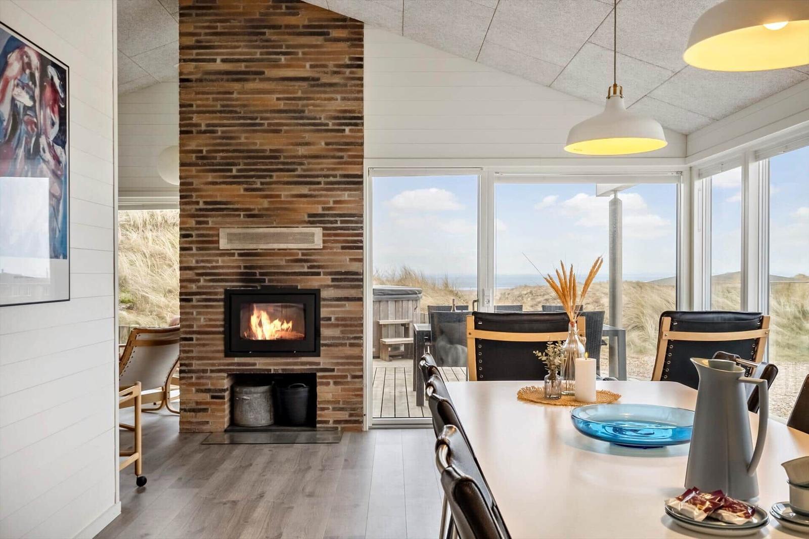 Essbereich mit Kamin und Blick auf Dünen.