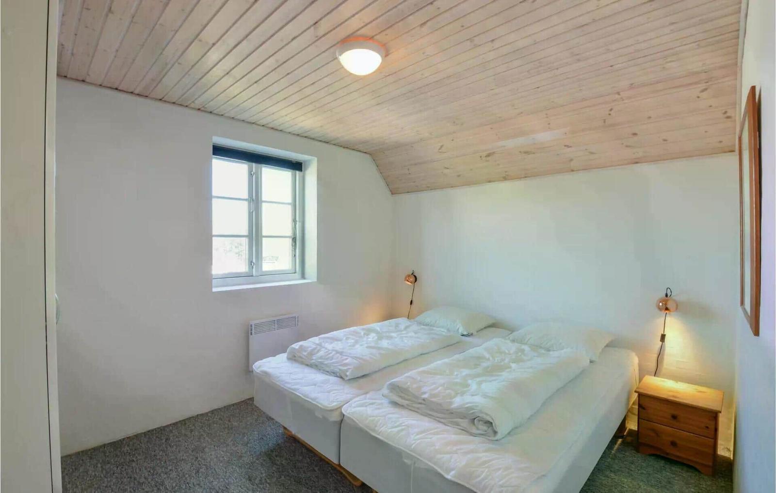 Schlafzimmer mit Doppelbett, Holzdecke und Fenster