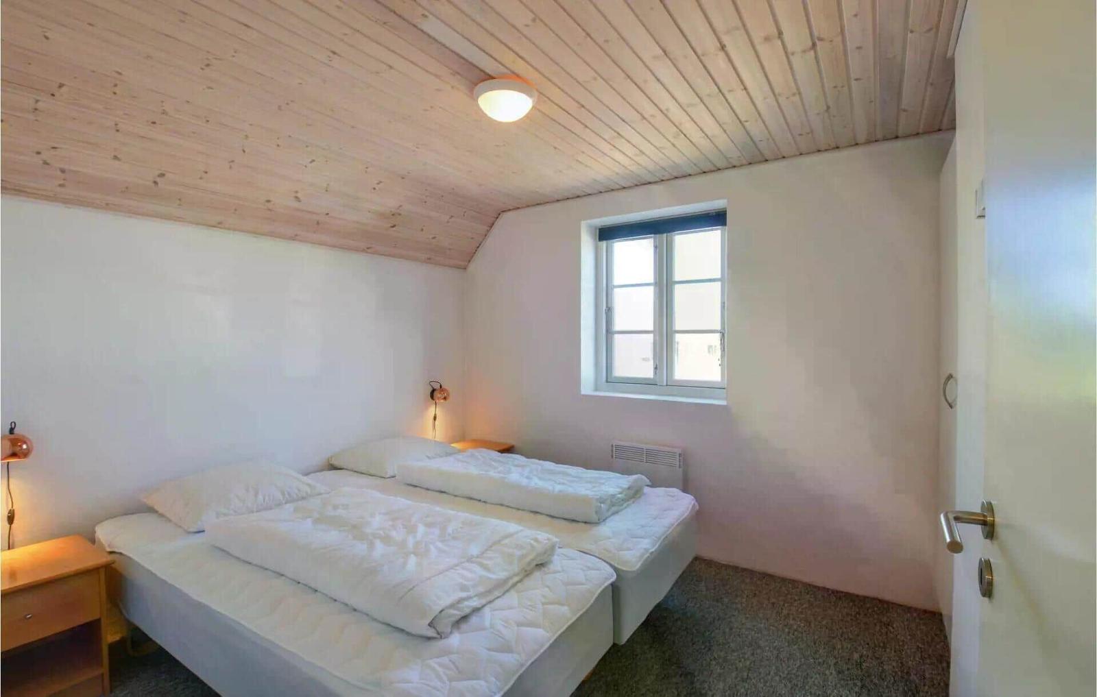 Schlafzimmer mit Doppelbett, Holzdecke und Fenster.