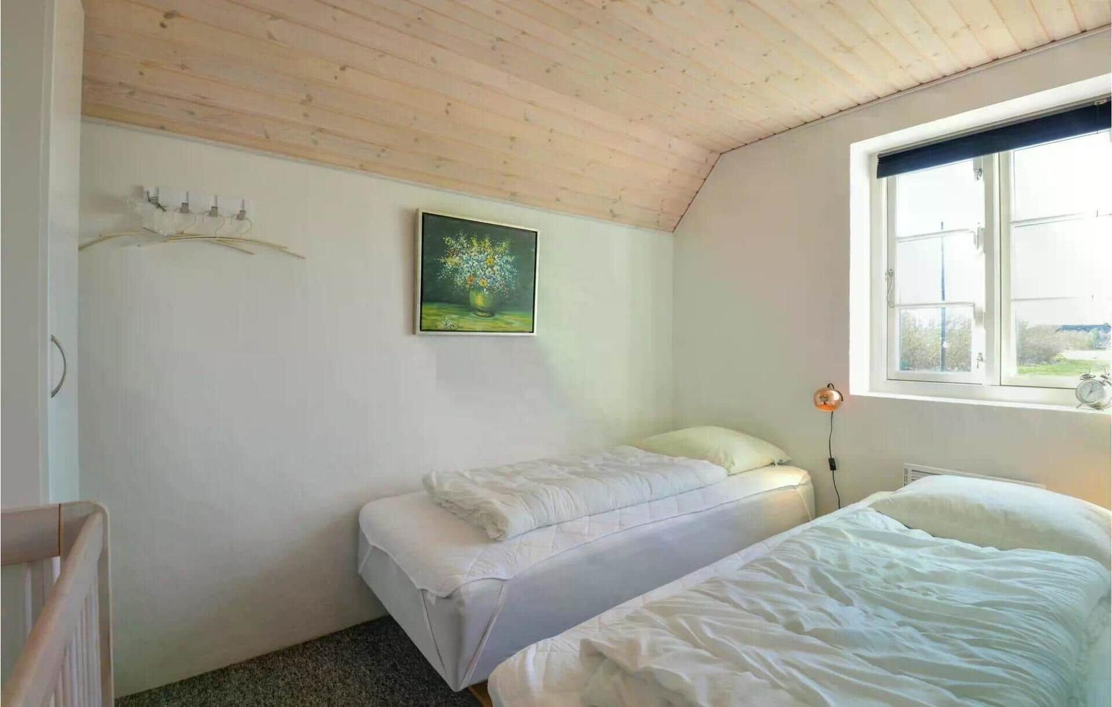 Zwei Betten, Fenster, Wandbild und Holzdecke im Schlafzimmer.
