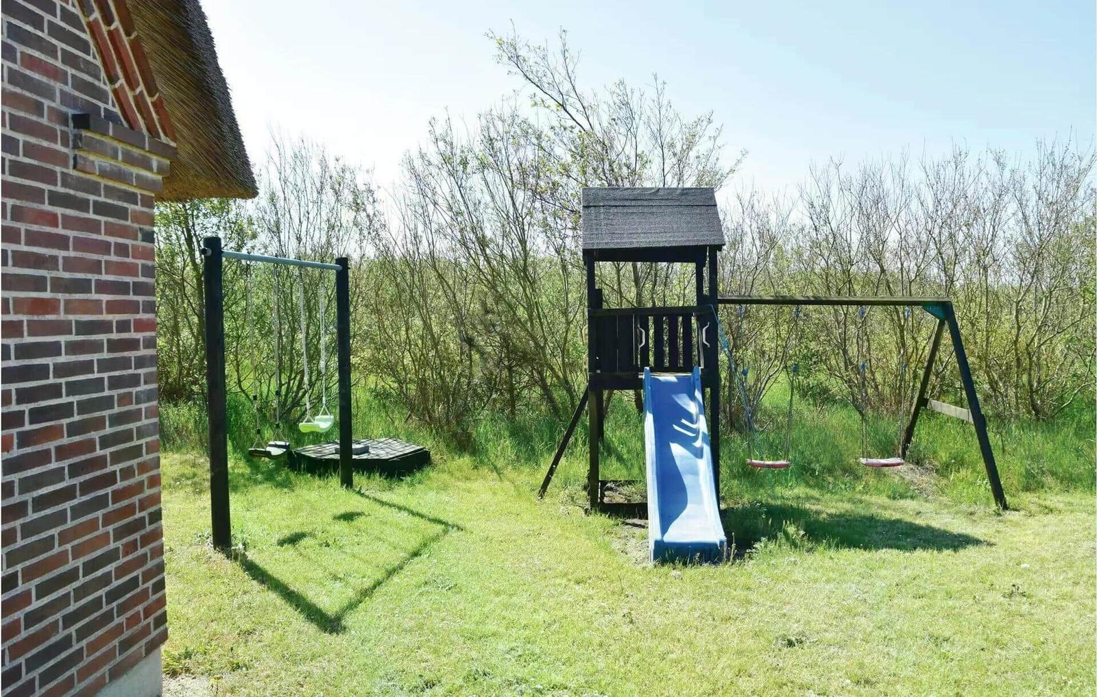 Hinter dem Haus befindet sich ein Spielplatz mit Rutsche und Schaukel.