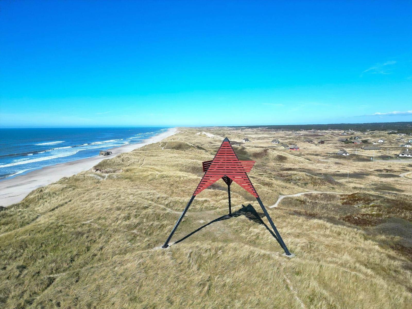 Roter Stern auf Dünen mit Blick auf Strand und Meer.