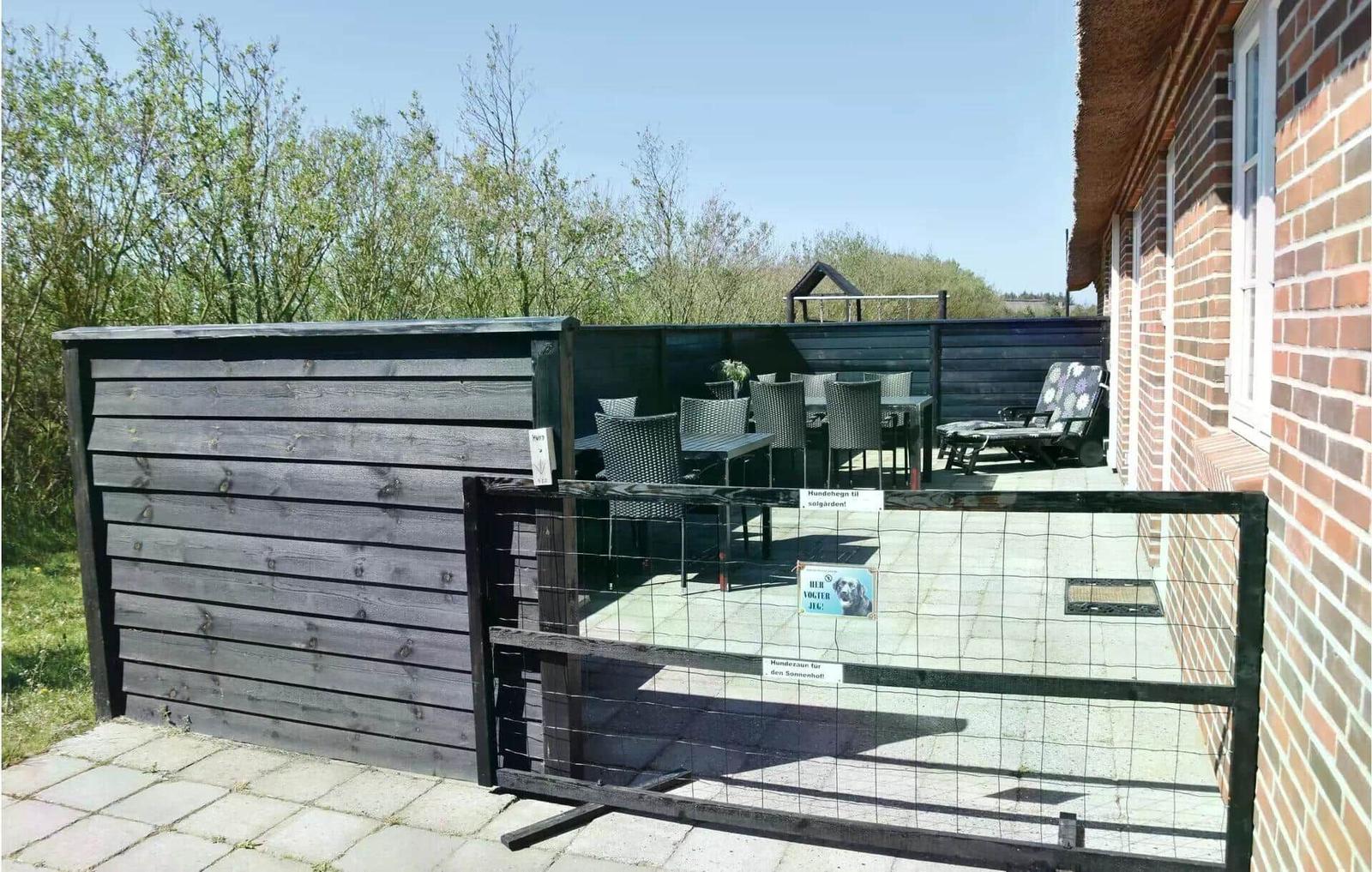Hundegitter und Terrasse mit Tisch, Stühlen und Liege