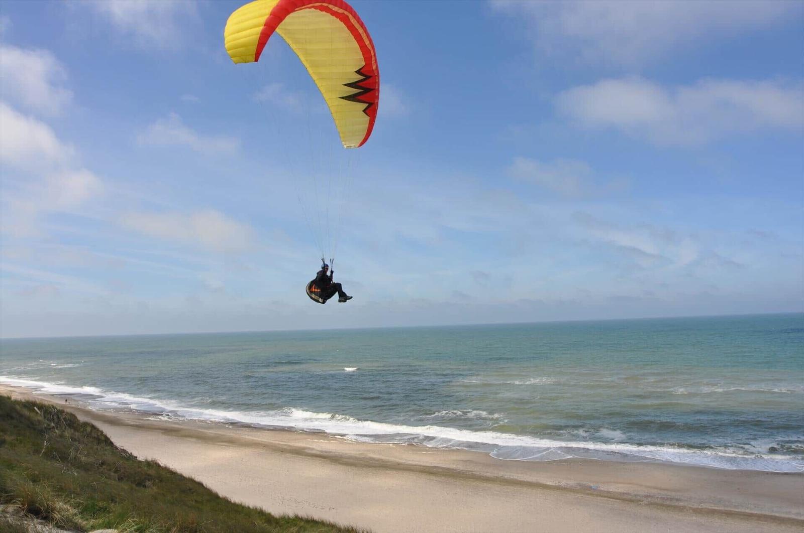 Paraglider fliegt über Strand und Meer.