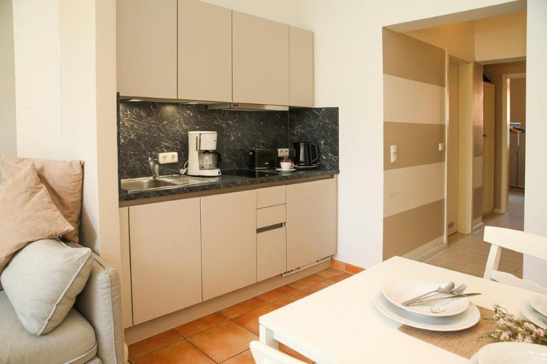 Küche mit Arbeitsplatte, Spüle und Küchengeräten. Tisch mit Geschirr und Stühlen.