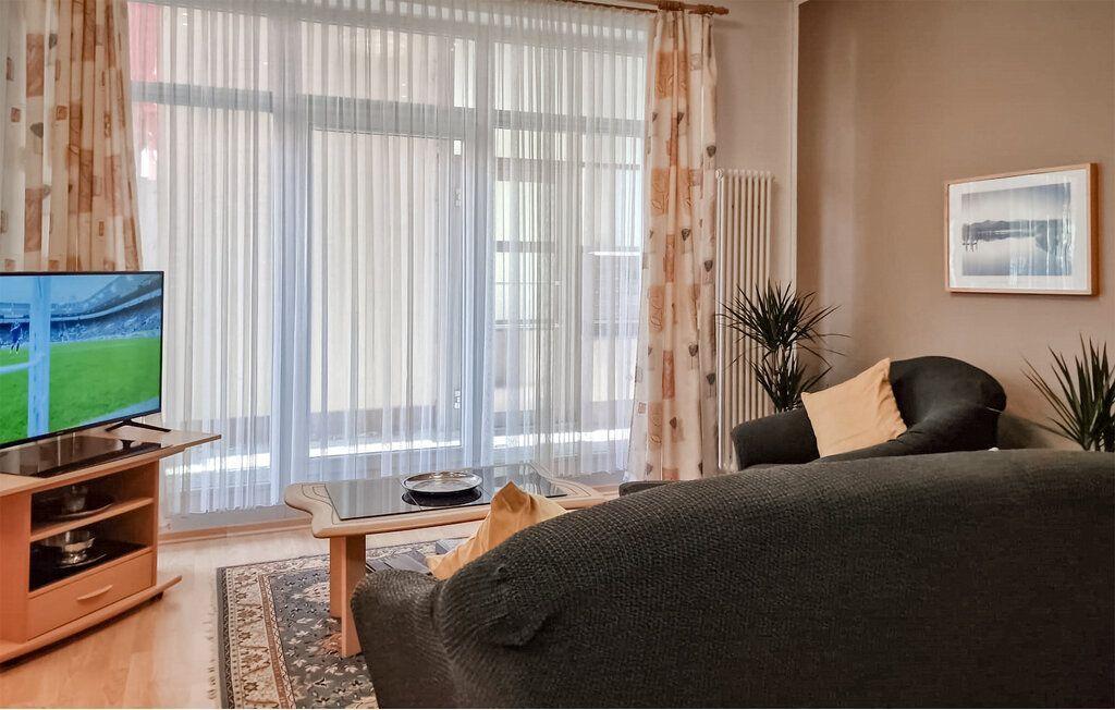 Wohnzimmer mit Sofa, Fernseher und großem Fenster