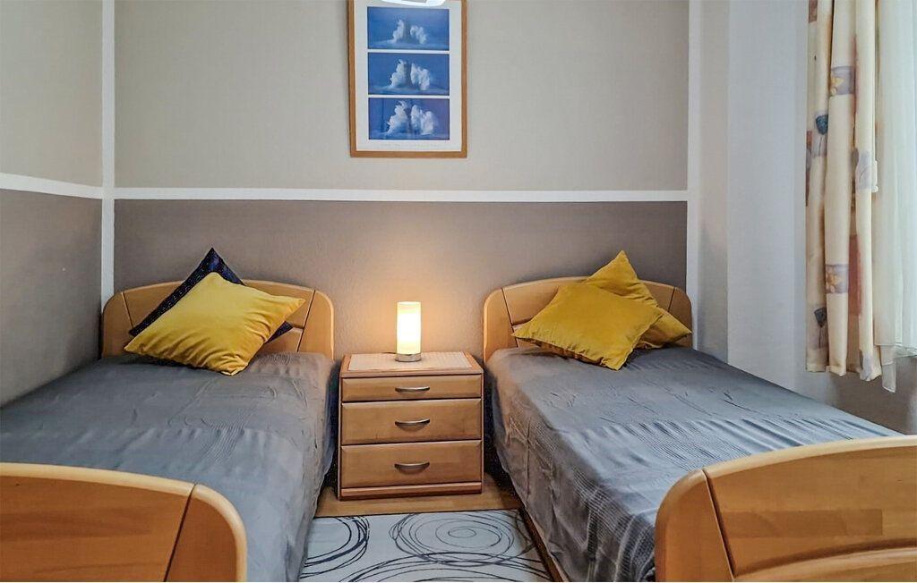 Zwei Einzelbetten mit gelben Kissen und Nachttisch dazwischen.