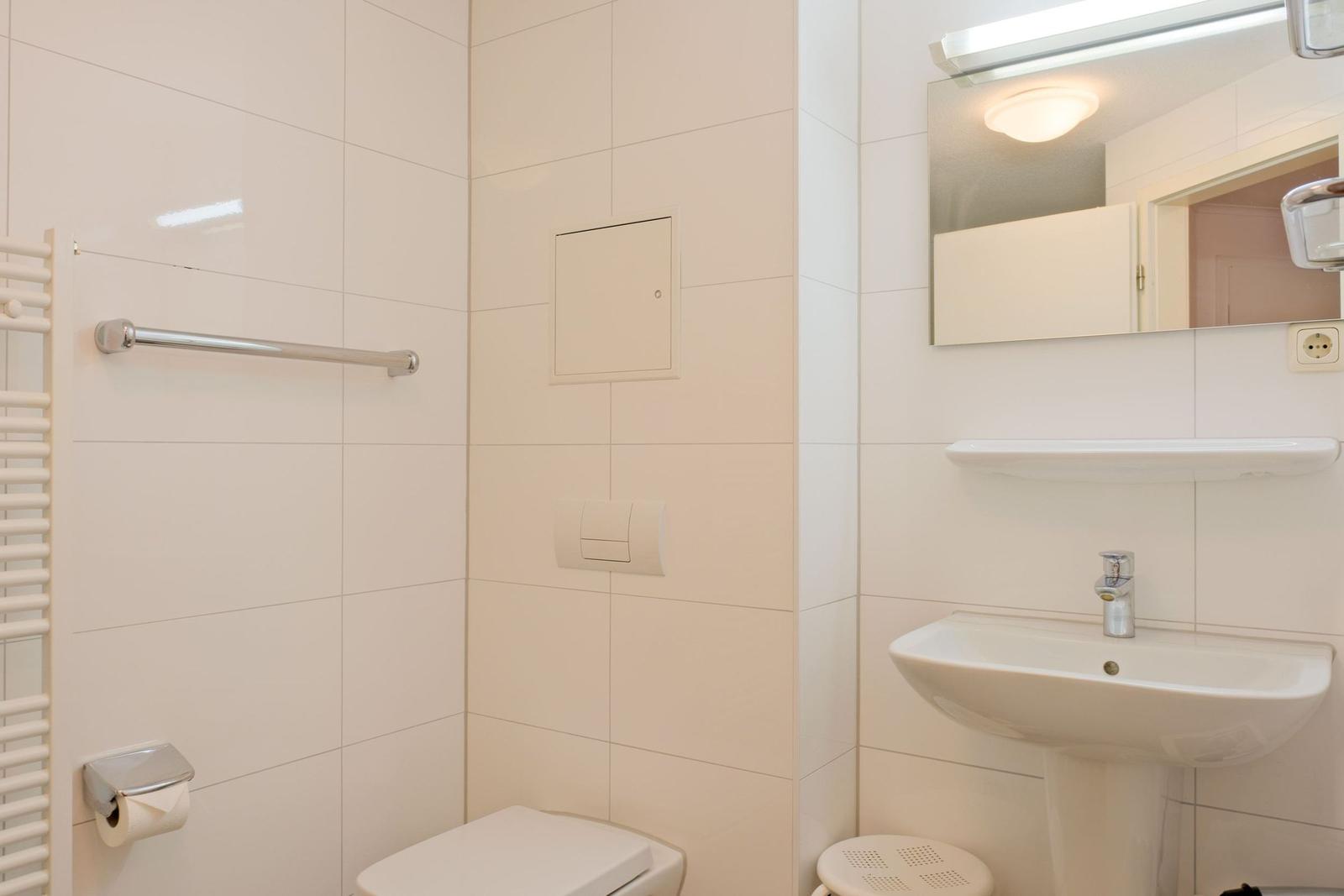 Badezimmer mit Toilette, Waschbecken und Spiegel.
