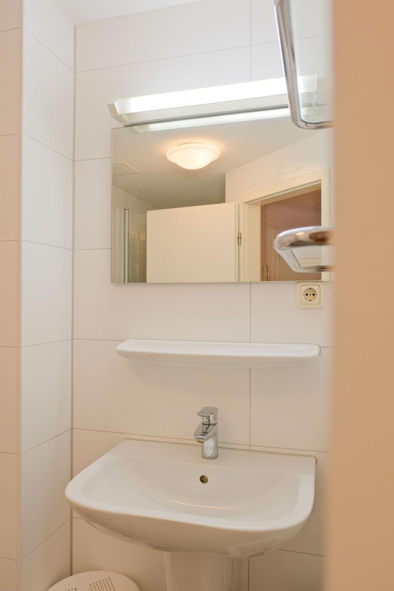Badezimmer mit Waschbecken, Spiegel und Licht