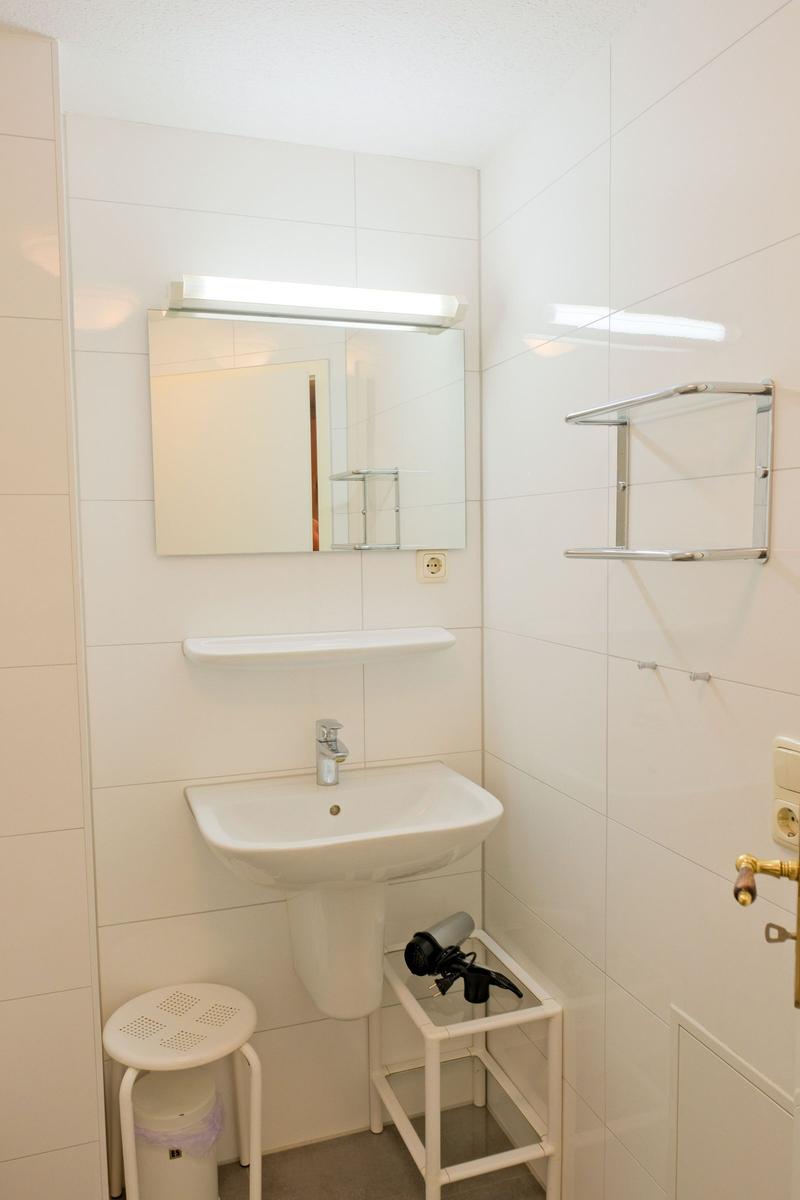 Badezimmer mit Waschbecken, Spiegel und Handtuchhalter.