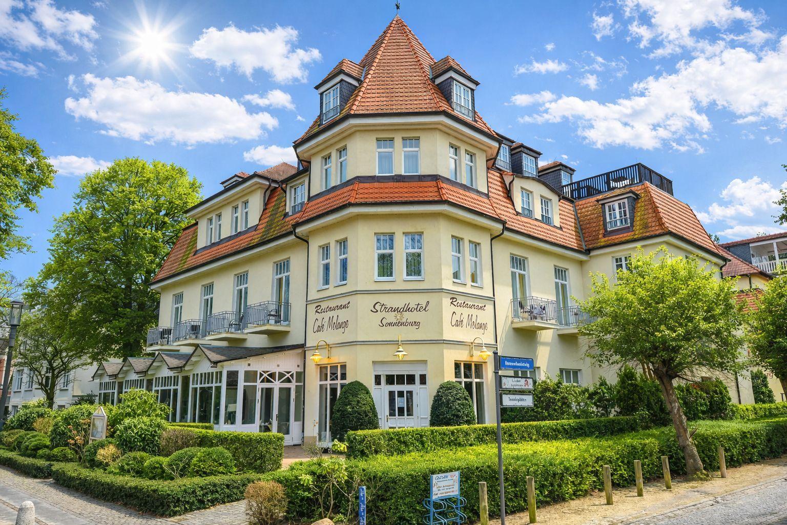 Strandhotel Sonnenburg mit Café Melange und rotem Ziegeldach unter blauem Himmel.