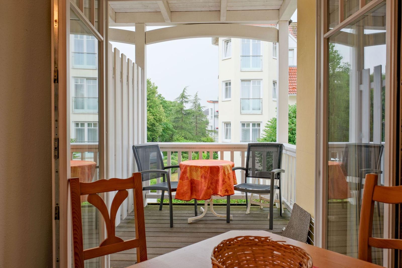 Terrasse mit Tisch, zwei Stühlen und orangefarbener Tischdecke.