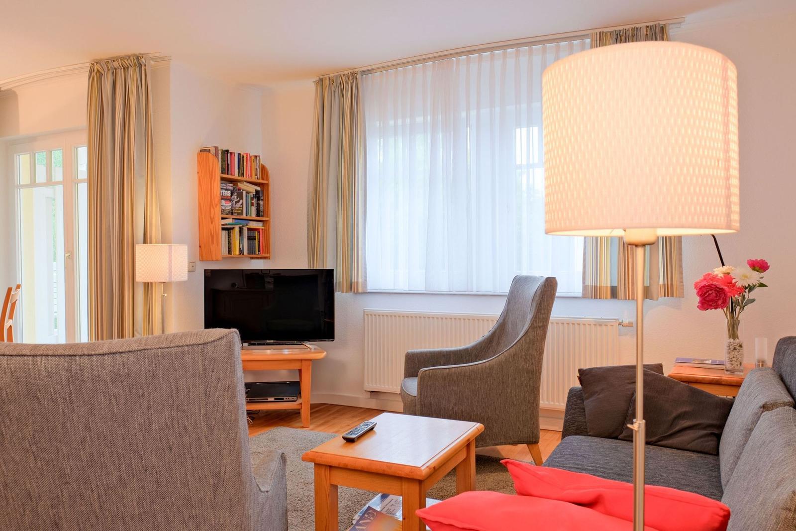 Wohnzimmer mit Sofa, Sessel, Fernseher und Tisch.