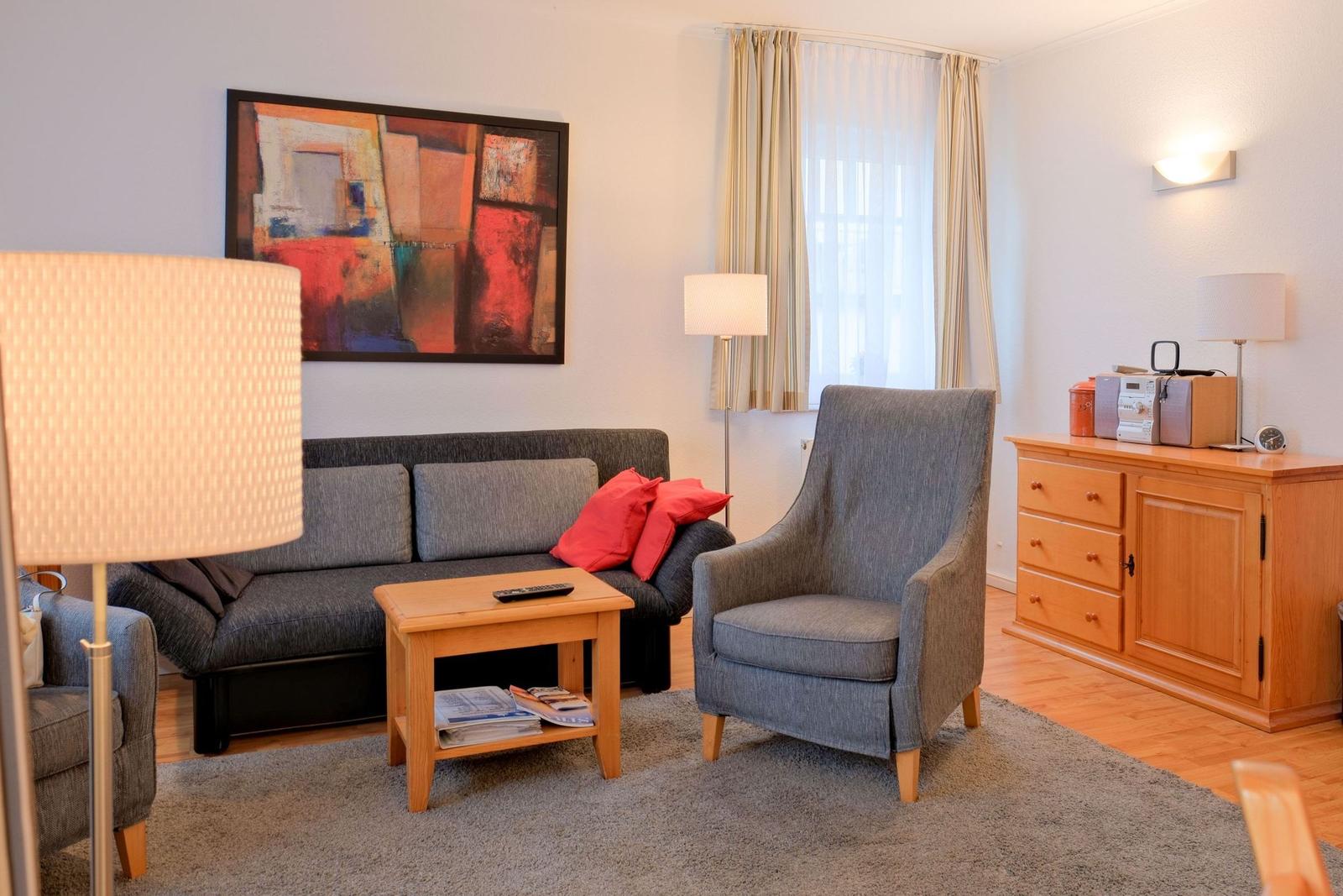 Wohnzimmer mit Sofa, Sessel, Couchtisch und Wandbild.