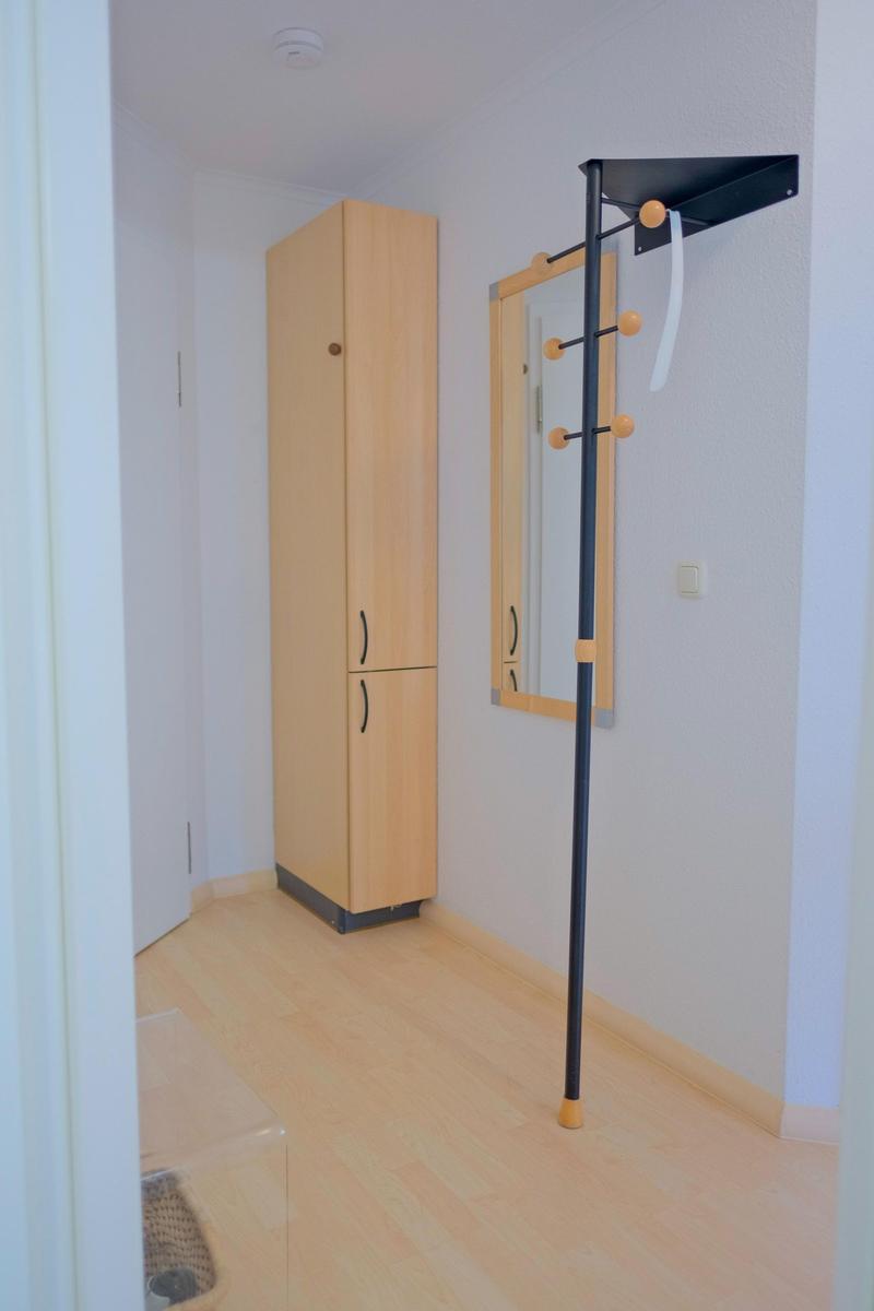 Flur mit Kleiderständer, Spiegel und Schrank.