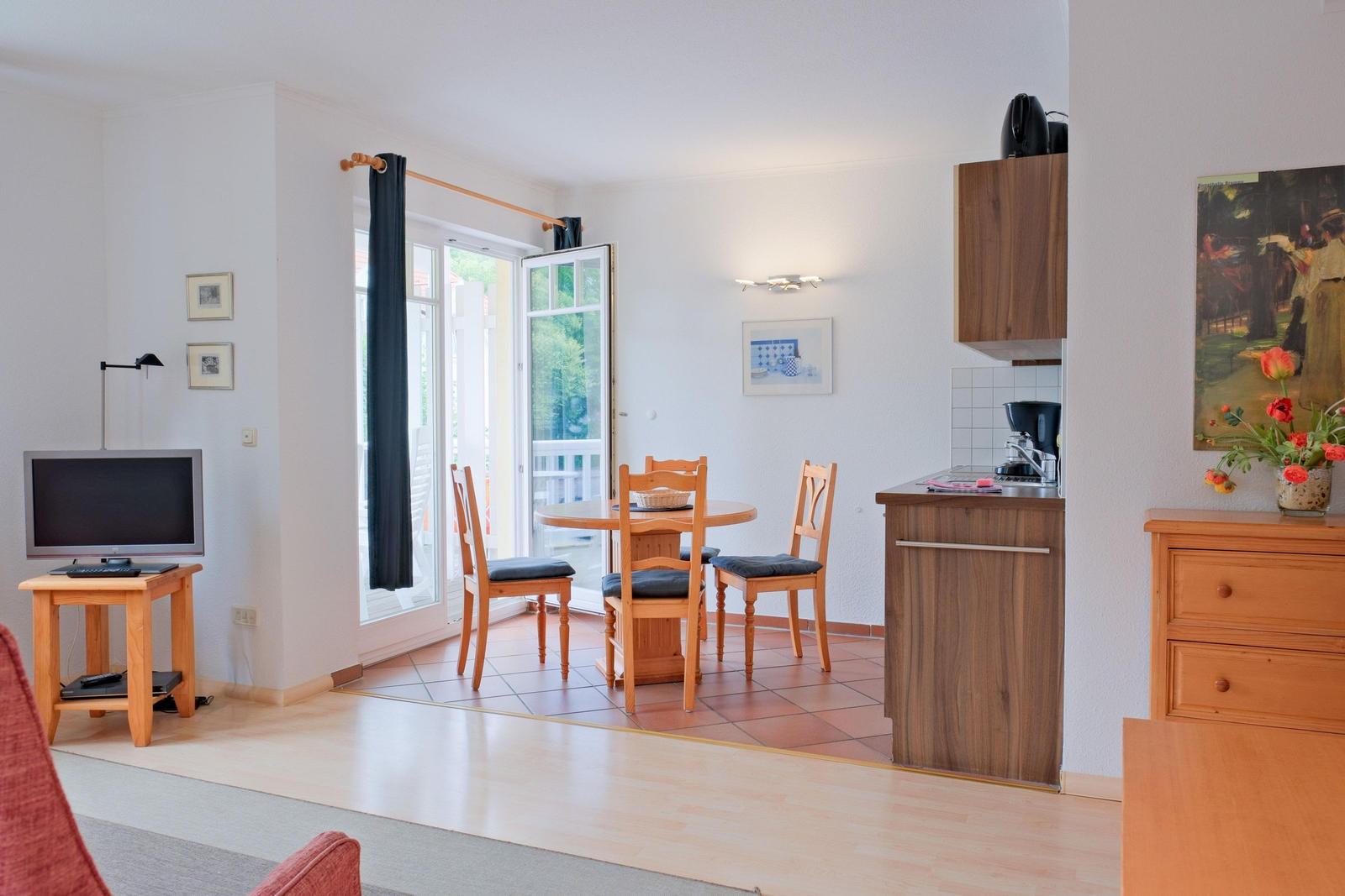 Wohnküchenbereich mit Essplatz, TV und Blick auf Balkon.